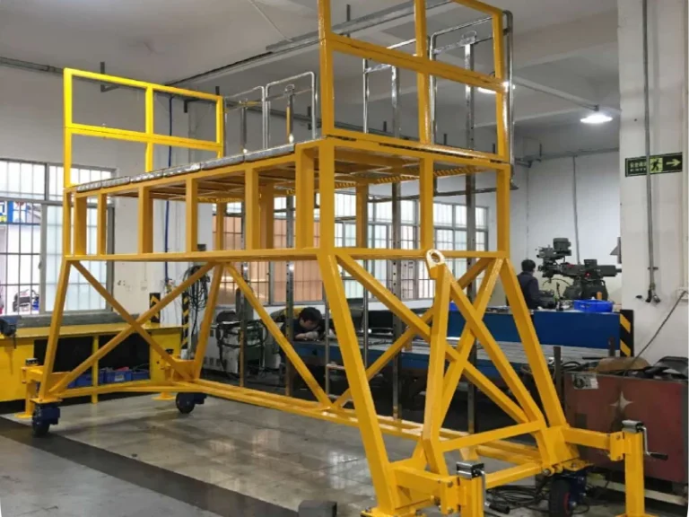 Heavy-duty aviation landing gear maintenance platform with continuous safety guardrails and anti-slip grating inside a manufacturing facility.